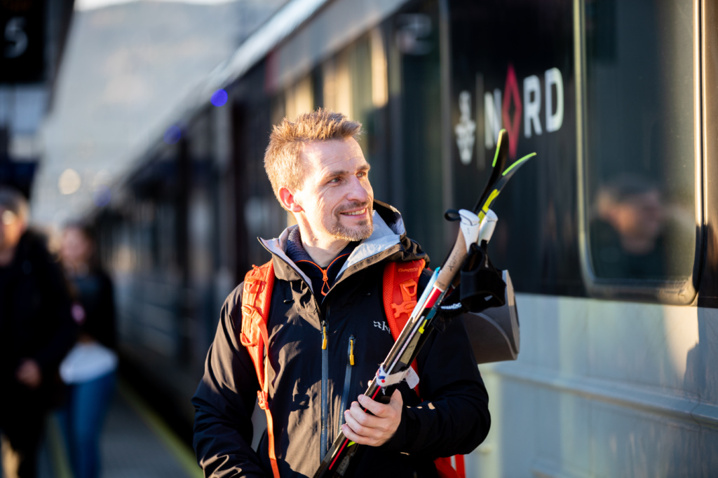 Man holder et par ski på perrongen