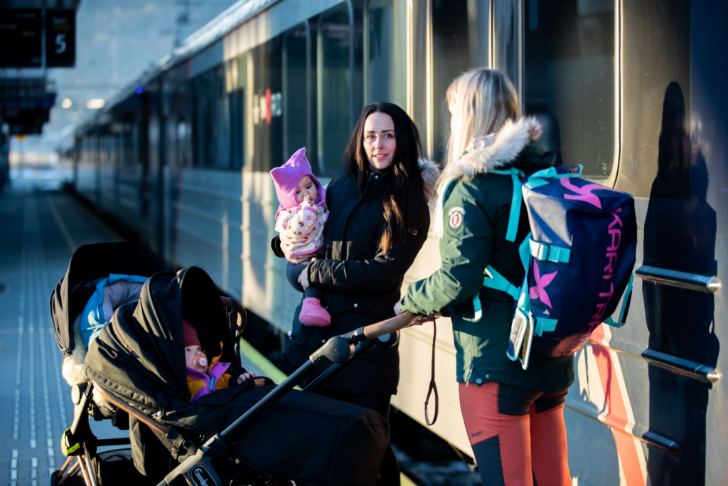 Women and baby with a stroller waiting to go on board the train