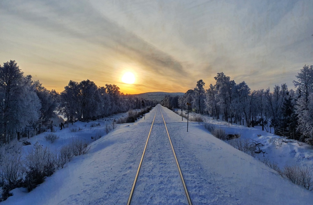 Panoramabilde av en snødd togspor og sola